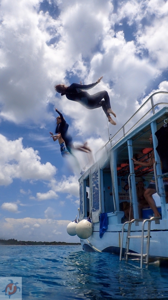 Tourists jumping off boat on Snorkel tour